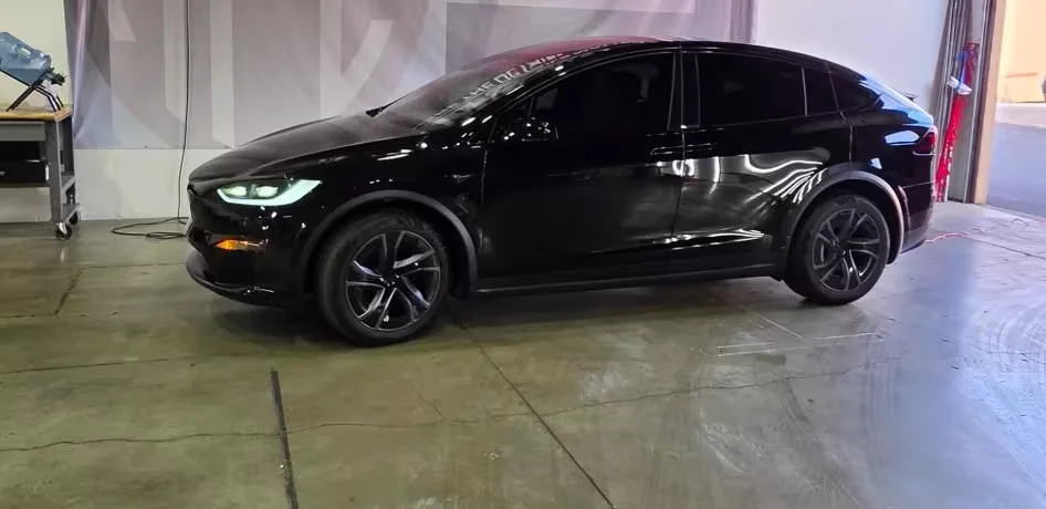 A glossy black Tesla Model X parked inside the APC Auto Spa shop